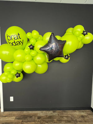 Brat party decorations and photo shoot backdrop with a Charlie XCX grab and go balloon garland kit in lime green with black foil star balloons for a teen birthday party or tween birthday party.