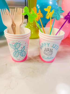 Disposable forks and balloon animal cupcake toppers arranged inside custom paper cups for a 12 year old birthday party with a gender neutral theme.