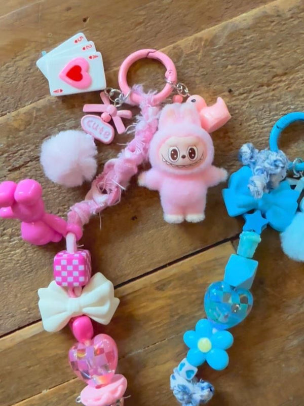 Birthday party favors or party activity ideas for tweens or kids parties, with a charm bar kit to make your own backpack keychain with a pink labubu charm and blue flower charms.