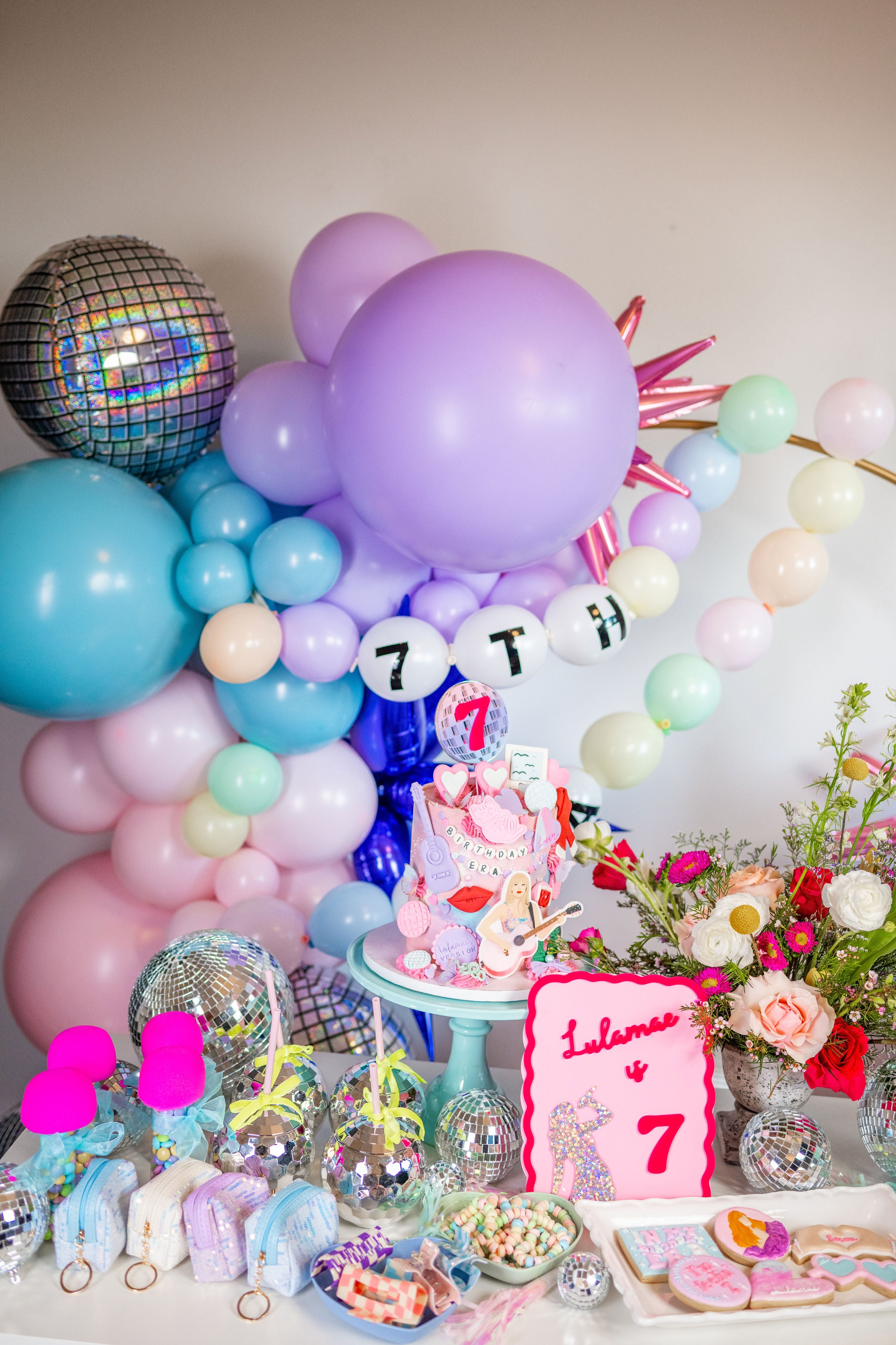 Taylor Swift birthday party inspiration featuring an in my birthday era balloon garland diy kit, Swiftie party favors, and cake table decor ideas.