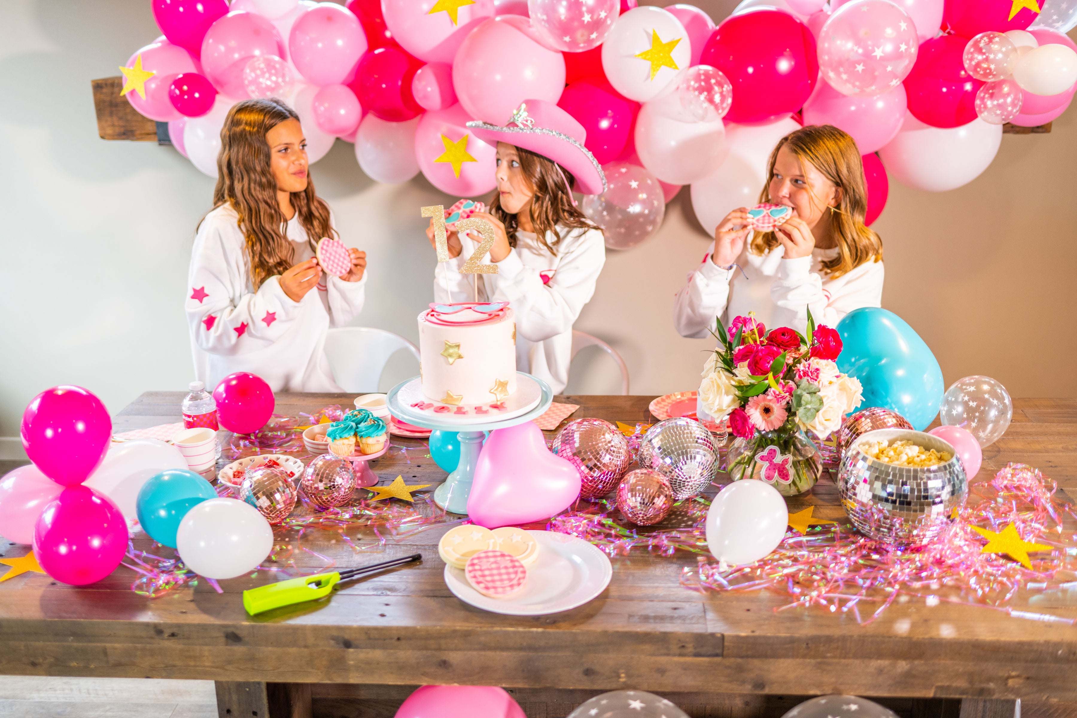 Barbie birthday party inspiration for teens or tweens with a DIY pink balloon garland kit, metallic pink fringe decor, pink disco balls, and a Barbie cake table idea.