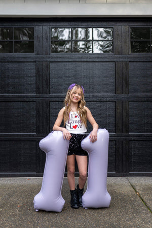 Balloon number decorations for an eleventh birthday party with an Olivia Rodrigo Guts theme for tweens.