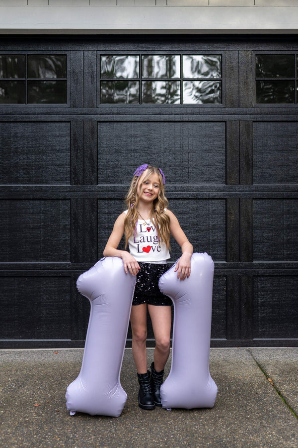 Balloon number decorations for an eleventh birthday party with an Olivia Rodrigo Guts theme for tweens.