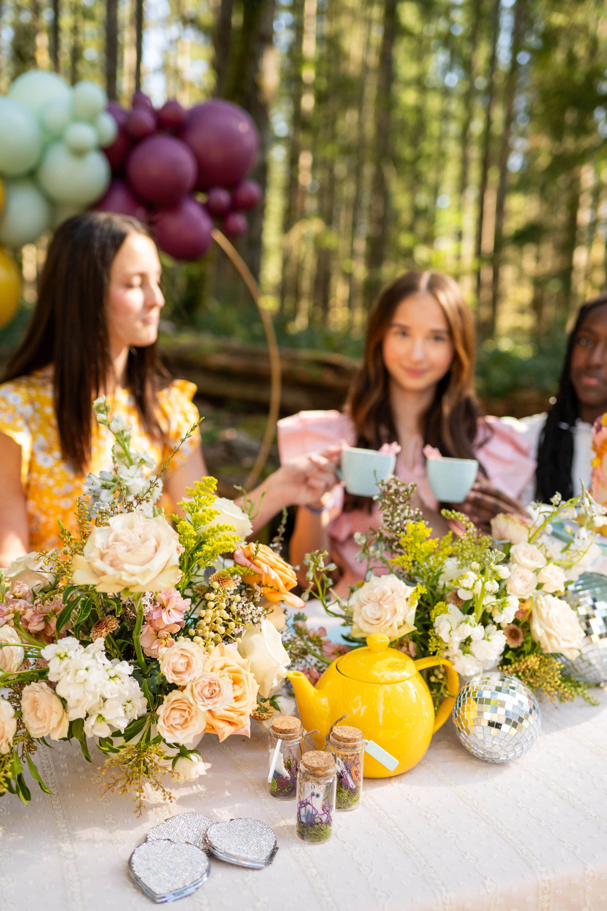 A tablescape idea for a Taylor Swift Anti Hero Midnights Birthday tea party in the woods, featuring a yellow teapot and an Evermore craft idea in a bottle.