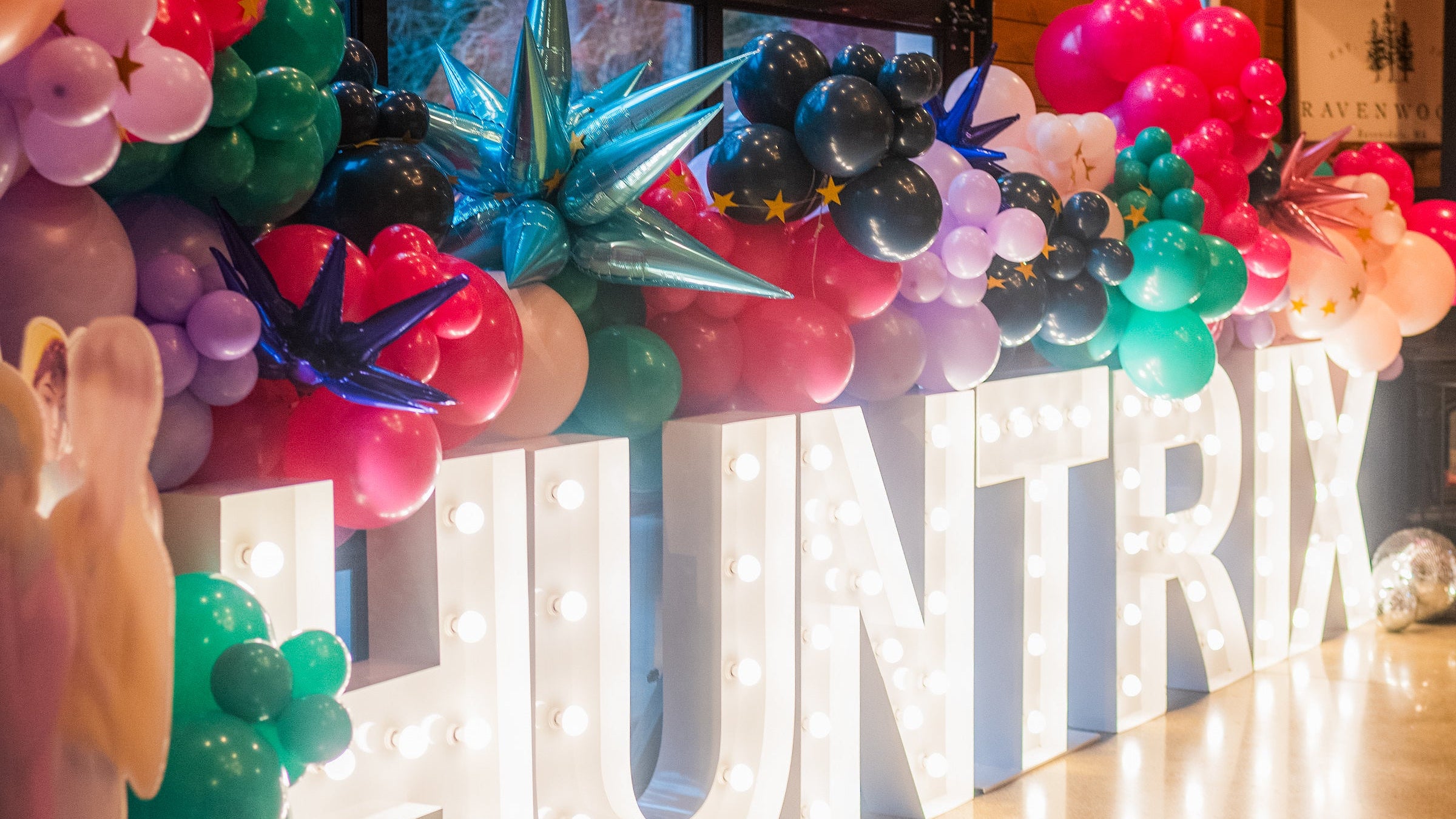Decorative setup with balloons and a large 'HUNTER' sign in a room with wooden walls.