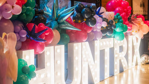 Huntrix marquee letters and a diy balloon garland kit for a kpop demon hunters birthday party for tweens or kids.