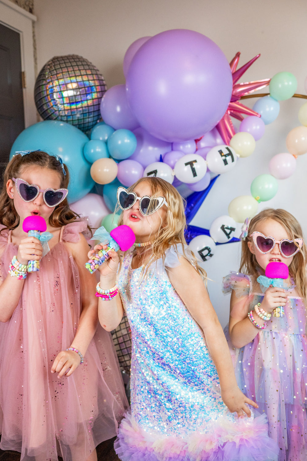 Three girls sing karaoke with microphone party favors at a Taylor Swift Eras Tour themed birthday party for kids, tweens, or teens.