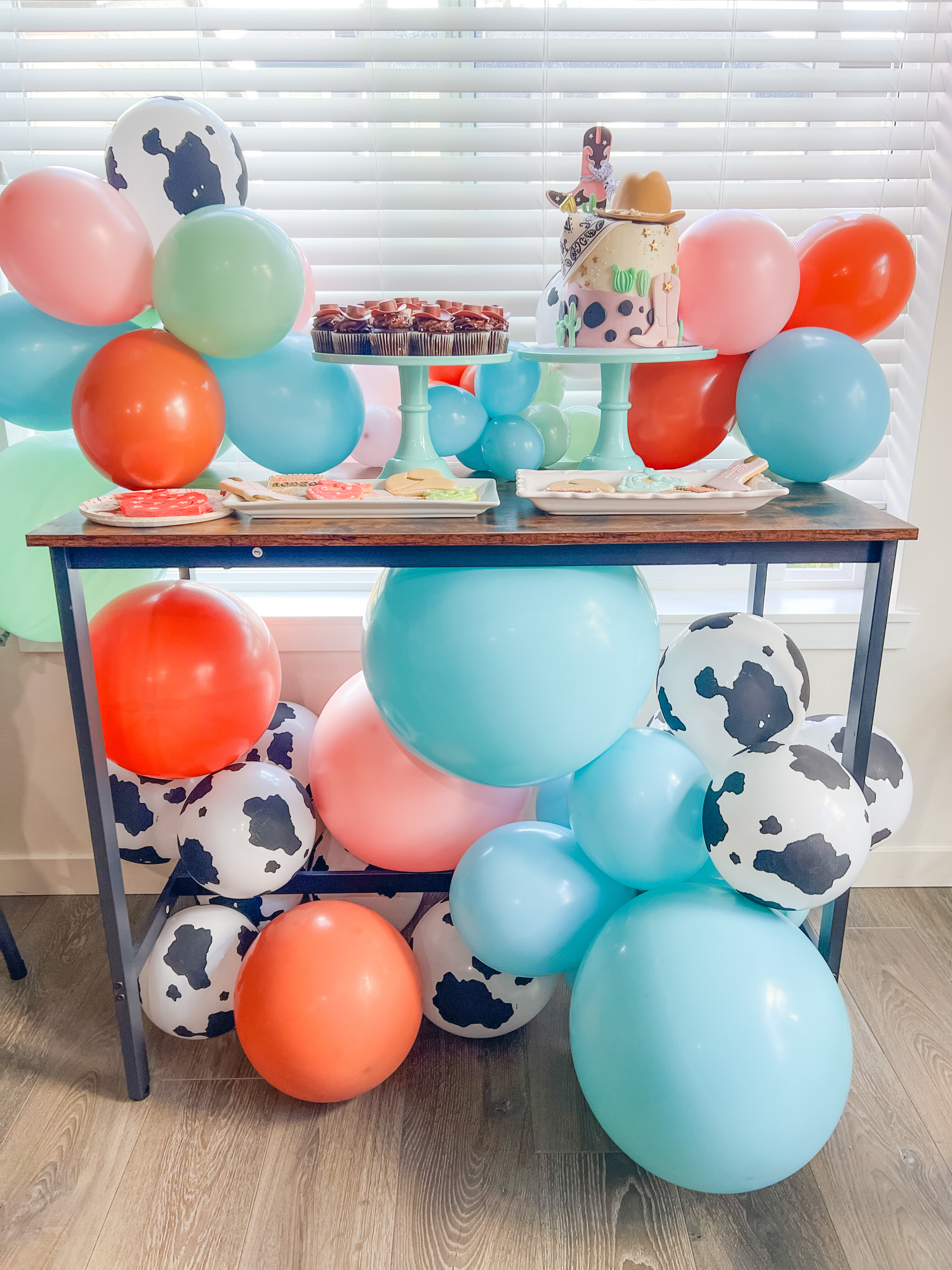 First birthday party ideas featuring one-year-old first rodeo theme decor, cow print balloons, and birthday party cake table inspiration.