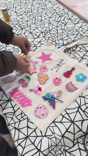 A decorate your own book bag patch bar kit for a Taylor Swift birthday party with Swiftie patches.