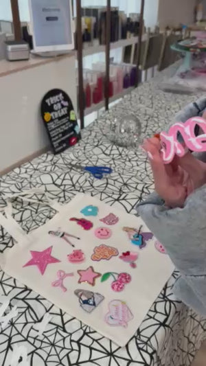 A decorate your own book bag party favor or party activity idea for a tween, teen, or kids birthday party for girls with a patch bar kit.
