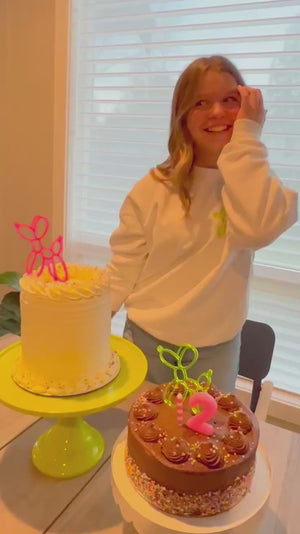 A girl grabs a piece of a birthday cake to eat at a 12th birthday party photoshoot.
