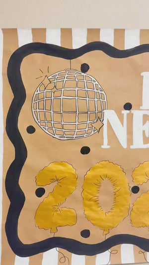 A video of a custom hand painted new years eve party banner featuring gold disco balls.